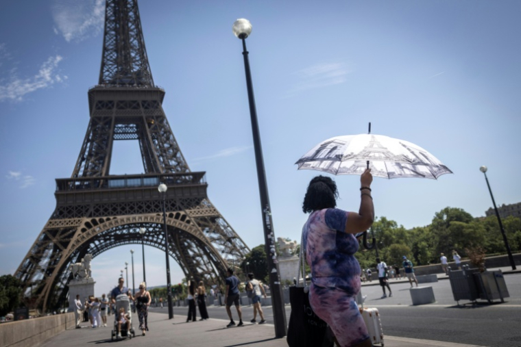 Une touriste se protège du soleil sous un parapluie, le 10 juillet 2026 à Paris  ( AFP / Behrouz MEHRI )
