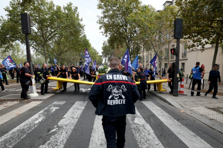Un pompier portant une inscription "En grève" participe à une manifestation organisée par une large coalition de syndicats, à Paris, le 28 septembre 2026 ( AFP / Xavier GALIANA )