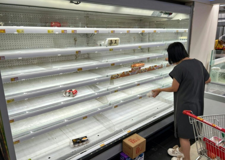 Une femme se tient devant un rayon de supermarché quasiment vidé à Hong Kong alors que le super typhon Ragasa approche de la ville, le 23 septembre 2025 ( AFP / Mladen ANTONOV )