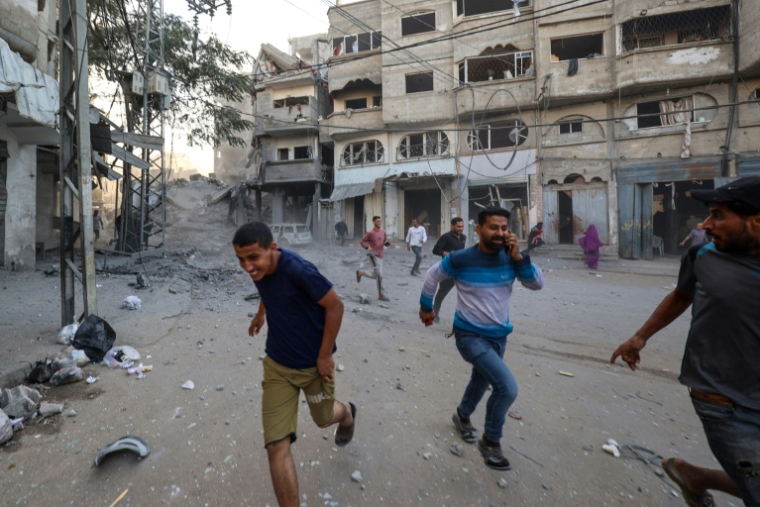 Des Palestiniens courent pour se mettre à l'abri après une frappe israélienne à Bureij, dans le centre de la bande de Gaza, le 19 octobre 2025 ( AFP / Eyad BABA )