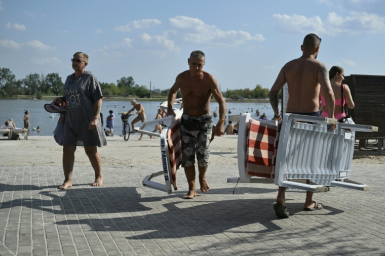 Des personnes se détendent sur les rives du lac Sloviansk, dans la région de Donetsk, le 6 août 2025 ( AFP / Genya SAVILOV )