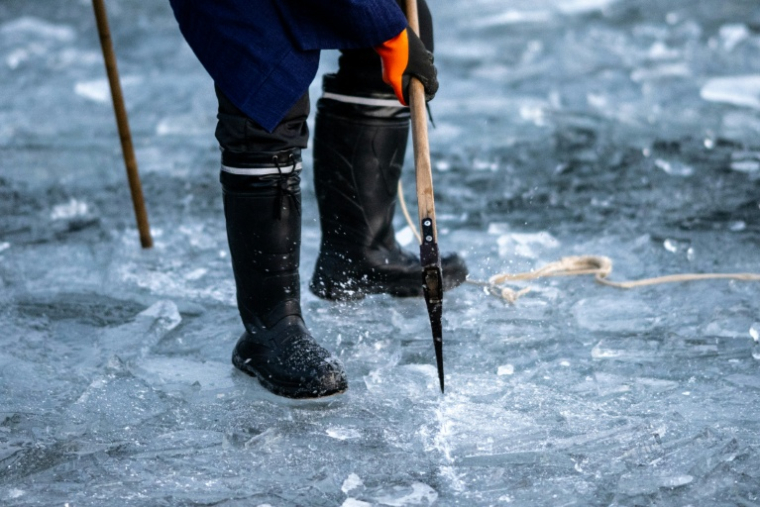Un fidèle du culte shinto brise de la glace avec une hache sur le lac Suwa, le 29 janvier 2026 dans la préfecture de Nagano, dans le centre du Japon  ( AFP / Philip FONG )