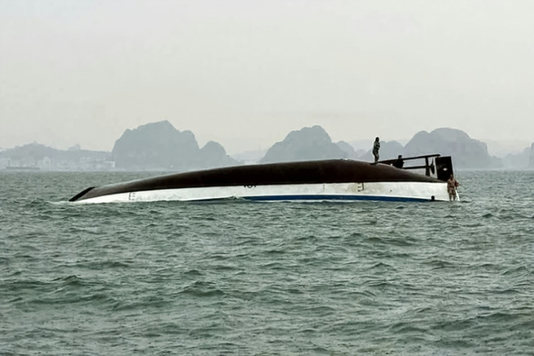 Un homme se tient sur un bateau touristique qui a chaviré dans la baie d'Halong, le 19 juillet 2025 ( AFP / - )