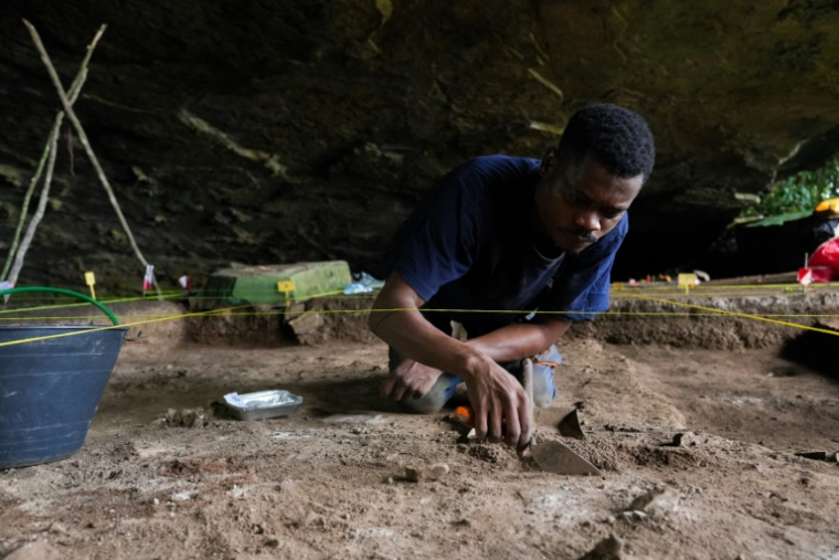 Un étudiant en archéologie fouille la grotte de Youmbidi, au Gabon, le 27 juin 2025 ( AFP / Nao Mukadi )