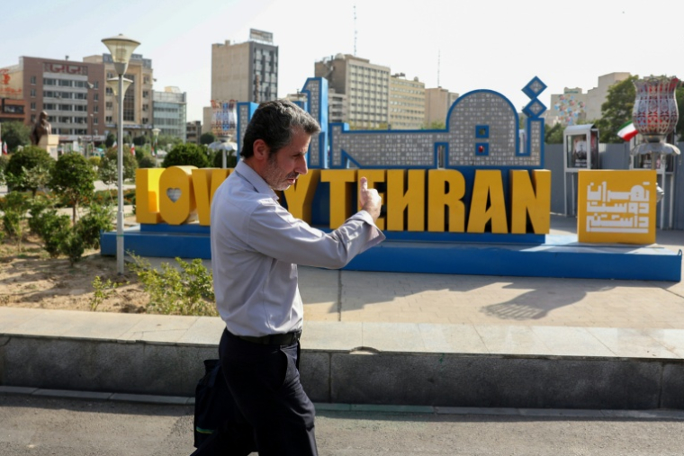 Un Iranien marche dans le centre de Téhéran le 23 juin 2025 ( AFP / ATTA KENARE )