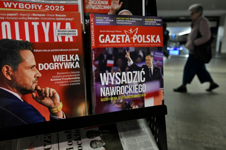 Une femme traverse un passage souterrain devant un kiosque vendant des magazines dont les Unes montrent les candidats à la présidentielle polonaise de 2025, Rafal Trzaskowski (g) et Karol Nawrocki (d), à Varsovie, le 19 mai 2025 ( AFP / Sergei GAPON )