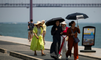 Un groupe de femmes porte des chapeaux et tient des ombrelles pour se protéger du soleil brûlant pendant la première vague de chaleur de l'année à Lisbonne, le 29 juin 2025 ( AFP / CARLOS COSTA )