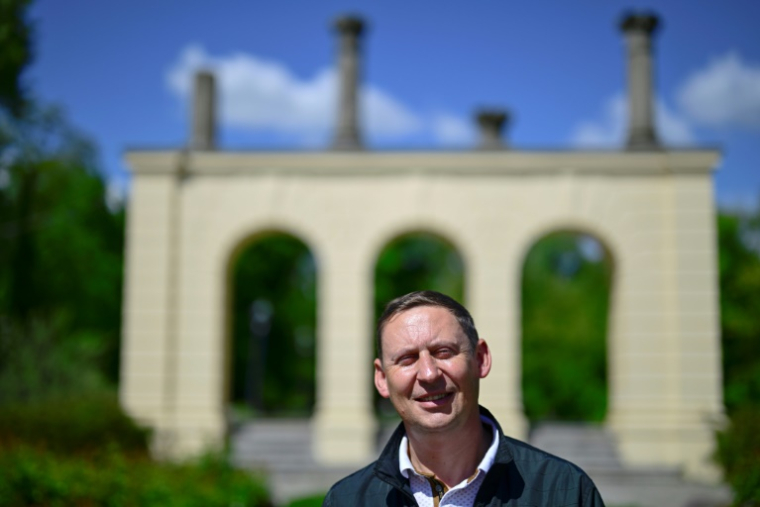 L'ancien maire de Gubin, Bartlomiej Bartczak, devant la ruine du théâtre de Gubin, sur l'île du théâtre sur la Neisse, le 9 mai 2025 ( AFP / John MACDOUGALL )