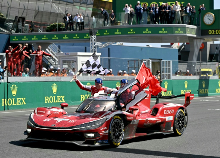 Mike Conway, Kamui Kobayashi et Nyck de Vries célèbre la victoire de la Toyota N.7 au Mans le 14 juin 2026 ( AFP / LOU BENOIST )