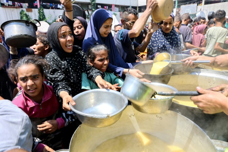 Des déplacés palestiniens reçoivent de la soupe aux lentilles dans un point de distribution de nourriture dans la ville de Gaza, le 25 juillet 2025 ( AFP / Omar AL-QATTAA )
