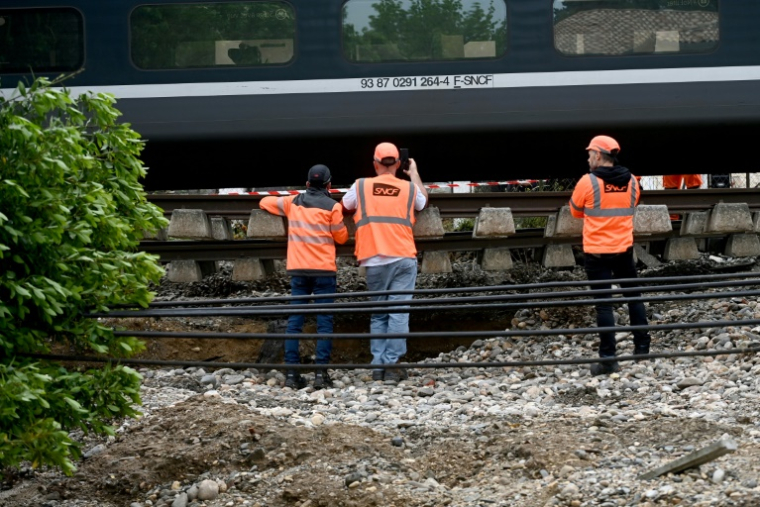 Des employés SNCF travaillent à côté d'un TGV reliant Toulouse à Bordeaux dont les ballasts situés sous la voie ferrée ont été emportés par le débordement d'un ruisseau en raison des intempéries, le 20 mai 2025, à Tonneins, dans le Lot-et-Garonne ( AFP / Christophe ARCHAMBAULT )