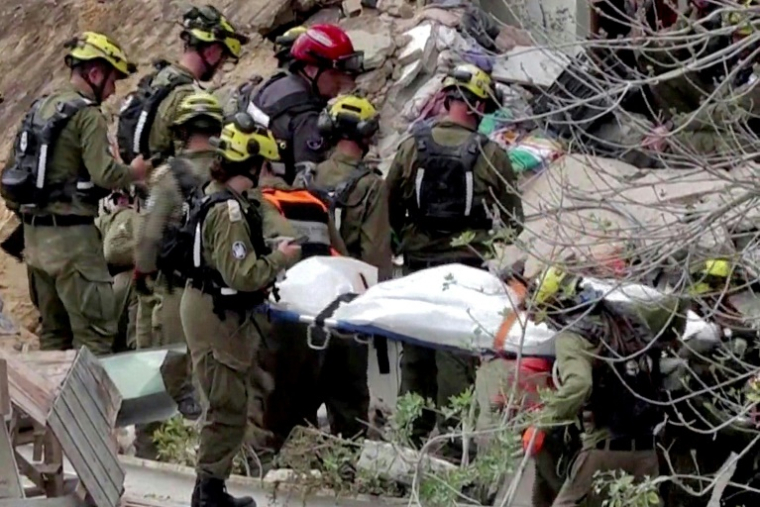 Image extraite d'une vidéo d’AFPTV montrant des équipes de secours israéliennes retirant des corps des décombres d’un immeuble résidentiel détruit par une attaque à missile iranien dans la ville de Haïfa le 6 avril 2026 ( AFPTV / Jorge NOVOMINSKY )