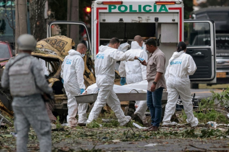 Des policiers portent le corps d'une victime morte dans une explosion à Cali, en Colombie, le 21 août 2025 ( AFP / Iusef Samir Rojas )