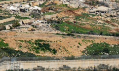 Des véhicules de combat de l'armée israélienne manœuvrent du côté israélien de la clôture frontalière, en face d'un village libanais détruit, vu de la Haute Galilée, dans le nord d'Israël, le 16 mars 2026 ( AFP / Odd ANDERSEN )