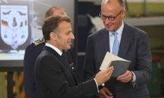Le chancelier allemand Friedrich Merz (D) et le président français Emmanuel Macron écoutent les explications d'un colonel à leur arrivée sur la base aérienne de Nörvenich, dans l’ouest de l'Allemagne, le 17 juillet 2026, où ils assisteront à une réunion du conseil de sécurité franco-allemand dans le cadre du conseil des ministres franco-allemand. ( AFP / Ludovic MARIN )