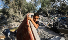 Un garçon palestinien récupère un matelas des décombres d'une maison après une frappe israélienne nocturne qui a touché Nousseirat, dans le centre de la bande de Gaza, le 13 juillet 2025 ( AFP / Eyad BABA )