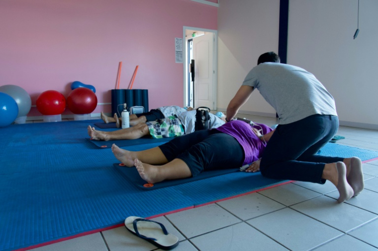 Un entraîneur aide des patients atteints d'obésité à faire des exercices de respiration au centre de santé spécialisé Ora Ora à Pirae, en Polynésie française, le 10 septembre 2021 ( AFP / Suliane FAVENNEC )