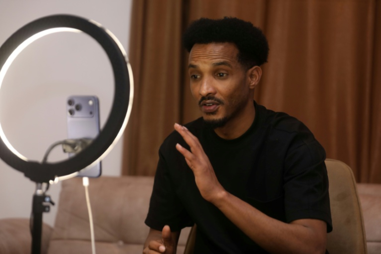 Mahad Maxamud interagit avec ses abonnés lors d'une diffusion en direct sur les réseaux sociaux depuis Mogadiscio, le 6 décembre 2025 ( AFP / Hassan Ali ELMI )