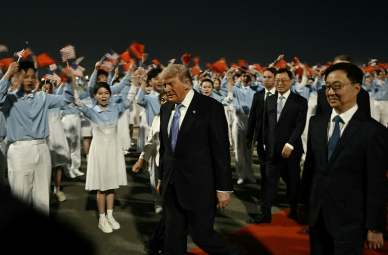 Le président américain Donald Trump (c) accompagné par le vice-président chinois Han Zheng (d) à son arrivée à l'aéroport international de Pékin, le 13 mai 2026 ( AFP / Brendan SMIALOWSKI )