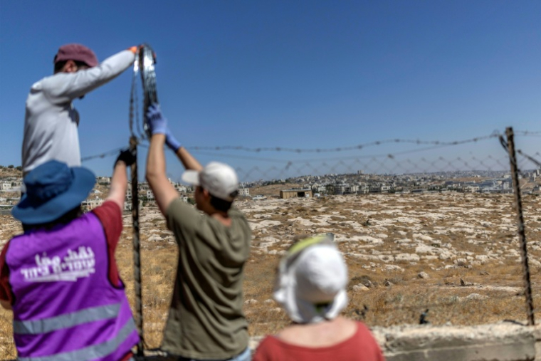 Des militants juifs pour la paix installent du fil barbelé pour ériger une barrière de protection autour d'une propriété palestinienne dans le village palestinien de Jannatah, situé en Cisjordanie occupée,  au sud de Bethléem, le 25 août 2026 ( AFP / Ilia YEFIMOVICH )