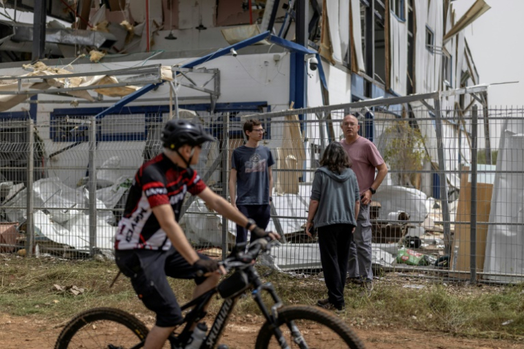 Des personnes observent les dégâts dans une usine touchée par un missile à Petah Tikva, à l’est de Tel-Aviv, le 3 avril 2026 ( AFP / Ilia YEFIMOVICH )