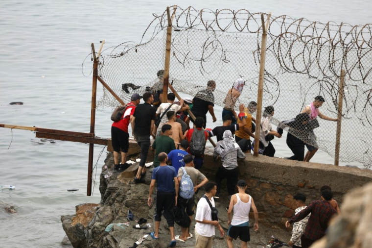 Des personnes sont rassemblées à côté d'une clôture près de Fnideq, à la frontière entre le Maroc et l'Espagne, le 31 juillet 2026 ( AFP / Abdel Majid BZIOUAT )