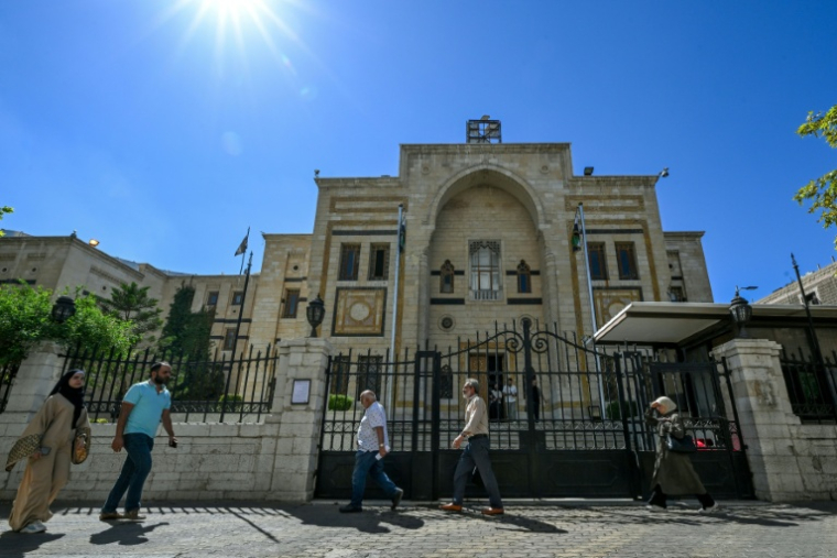Des personnes passent devant le bâtiment du Parlement à Damas, le 1er octobre 2025 ( AFP / Louai Beshara )