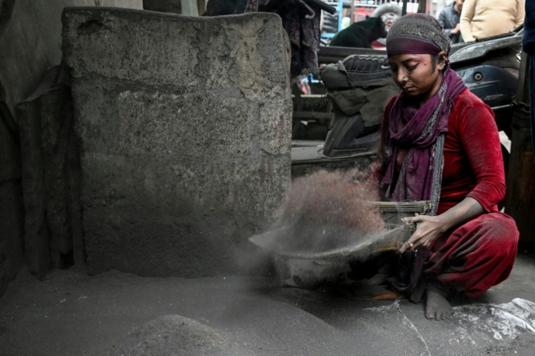 Une femme triant à la main le cuivre provenant des déchets de fils électriques dans un site informel de recyclage des déchets électroniques à Seelampur, New Delhi, le 28 janvier 2026 ( AFP / Arun SANKAR )