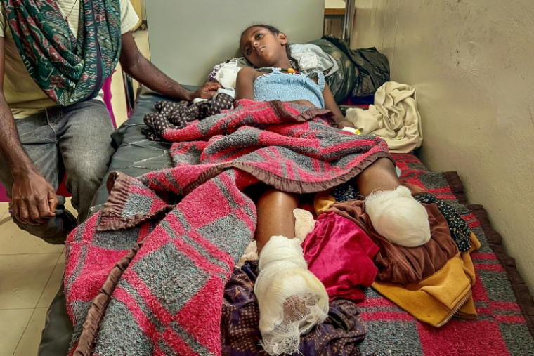 Iyerusalem, 10 ans, soigne ses blessures aux jambes le 6 octobre 2026, sur un lit de l'hôpital Ayder de Mekele, son père à ses côtés ( AFP / - )