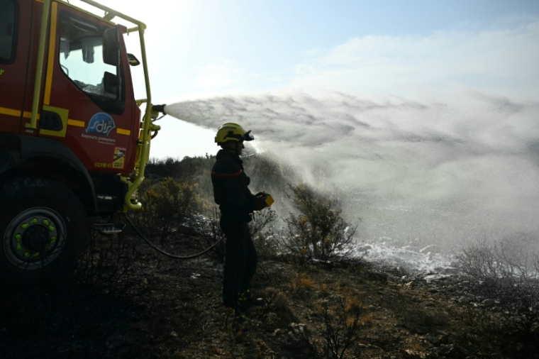 Des pompiers éteignent des cendres chaudes à côté d'Albas, dans le massif des Corbières, le 9 août 2025 ( AFP / Bertrand GUAY )