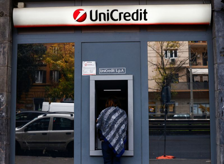 Une personne utilise un distributeur automatique de billets dans une agence bancaire UniCredit à Rome