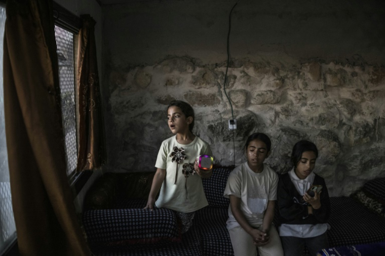 Les sœurs Layan, Bisan et Ni'ameh chantent au karaoké dans la grotte que leur famille a transformée en foyer, dans le village palestinien d'Al-Tuwani, en Cisjordanie occupée, le 11 septembre 2026 ( AFP / John WESSELS )