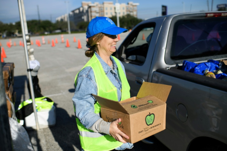 Une bénévole porte un carton lors d'une distribution d'aide alimentaire à Houston, au Texas, le 1er novembre 2025 ( AFP / Mark Felix )