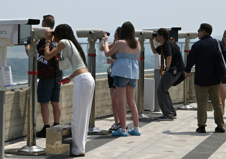 Des touristes utilisent des jumelles pour observer le territoire nord-coréen depuis une plate-forme d'observation sud-coréenne située à l'Écoparc de la Paix d'Aegibong, à Gimpo, le 1er juillet 2026  ( AFP / Jung Yeon-je )