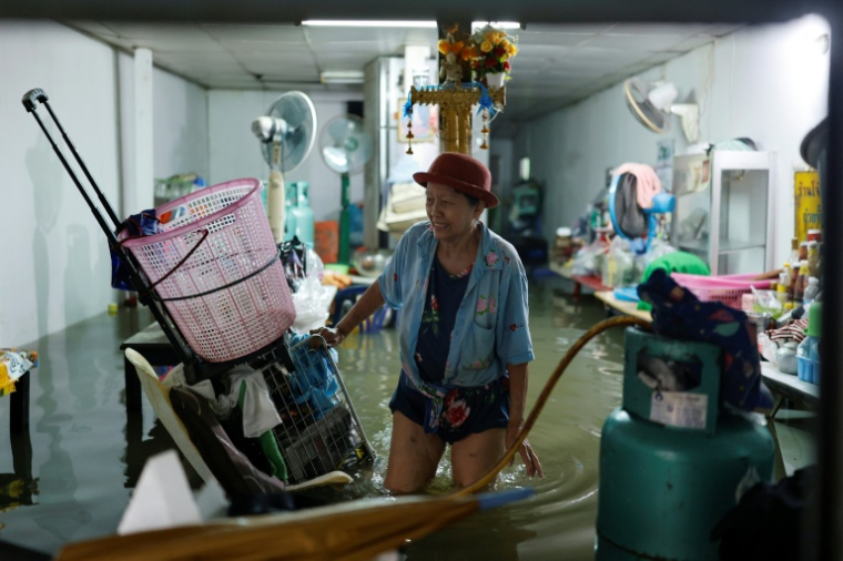 Une personne s'occupe de sa boutique inondée dans le district de Bang Bua, à Bangkok, le 26 septembre 2026 ( AFP / WIKUS DE WET )