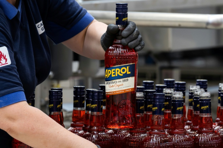 Un ouvrier de l'usine phare du groupe Campari à Novi Ligure, dans le nord-ouest de l'Italie, tient une bouteille d'Aperol, le 21 juillet 2026 ( AFP / Marco Bertorello )