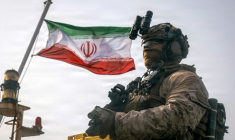 Cette photographie fournie par le Corps des Marines des États-Unis, prise le 16 juillet 2026 par le service des relations publiques du Commandement central américain, montrerait un drapeau iranien flottant derrière un marine américain de la 11e Unité expéditionnaire des Marines, dans le Golfe. ( US MARINE CORPS / Sgt. Joseph Helms )