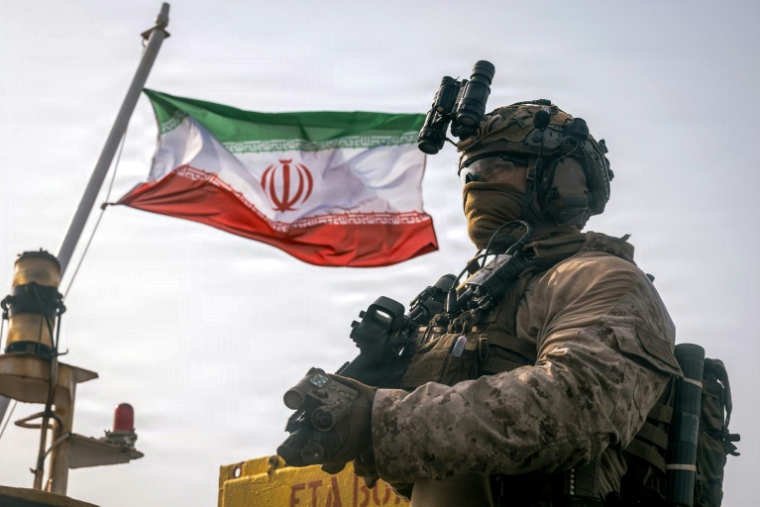Photo fournie par le Corps des Marines des États-Unis, prise le 16 juillet 2026 par le service de communication du Commandement central américain (USCENTCOM), montrerait un drapeau iranien flottant derrière un Marine de la 11e unité expéditionnaire des Marines lors d'une opération dans le golfe d'Oman ( US MARINE CORPS / Sgt. Joseph Helms )