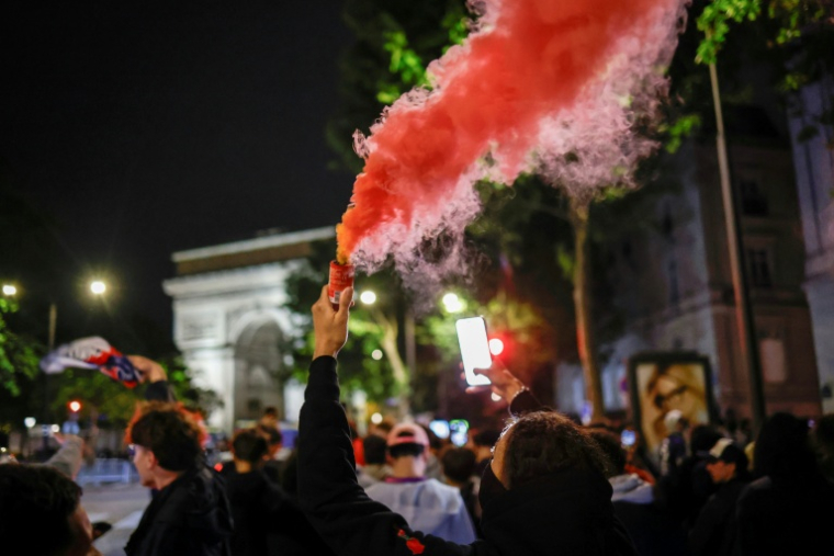 Des supporteurs du Paris Saint-Germain célèbrent la victoire après la qualification de leur équipe en finale de la Ligue des champions face au Bayern Munich, près de l'arc de Triomphe, le 6 mai 2026, à Paris ( AFP / SIMON WOHLFAHRT )