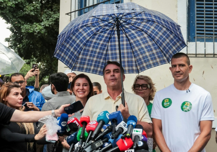 Le candidat à la présidence du Brésil, Flavio Bolsonaro, s'adresse aux journalistes aux côtés de son épouse Fernanda Bolsonaro (G) et de sa mère Rogeria Bolsonaro (2e à D, derrière), après avoir voté lors du second tour de l'élection présidentielle à Rio de Janeiro, au Brésil, le 25 octobre 2026 ( AFP / Douglas SHINEIDR )
