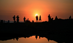 Des touristes profitent du soucher de soleil sur la plage d'El Tunco à La Libertad, au Salvador, le 13 février 2026 ( AFP / Marvin RECINOS )