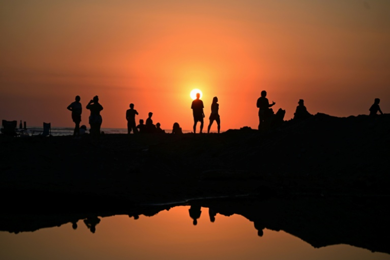 Des touristes profitent du soucher de soleil sur la plage d'El Tunco à La Libertad, au Salvador, le 13 février 2026 ( AFP / Marvin RECINOS )
