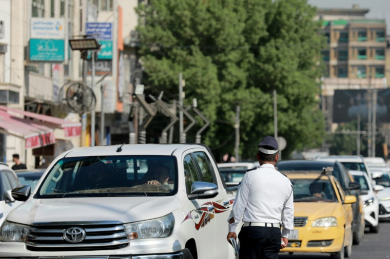Un policier devant une file d'automobilistes qui attendent devant une station-service à Bagdad, le 5 septembre 2026 en Irak ( AFP / Murtaja LATEEF )
