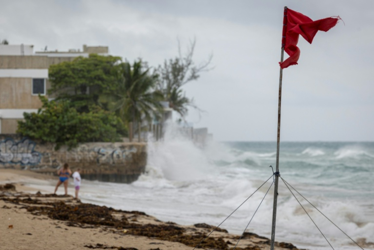 Un drapeau rouge déchiré par les vents violents à l'approche de l'ouragan Erin le 16 août 2025 sur l'île de Porto Rico (Etats-Unis) ( AFP / Ricardo ARDUENGO )