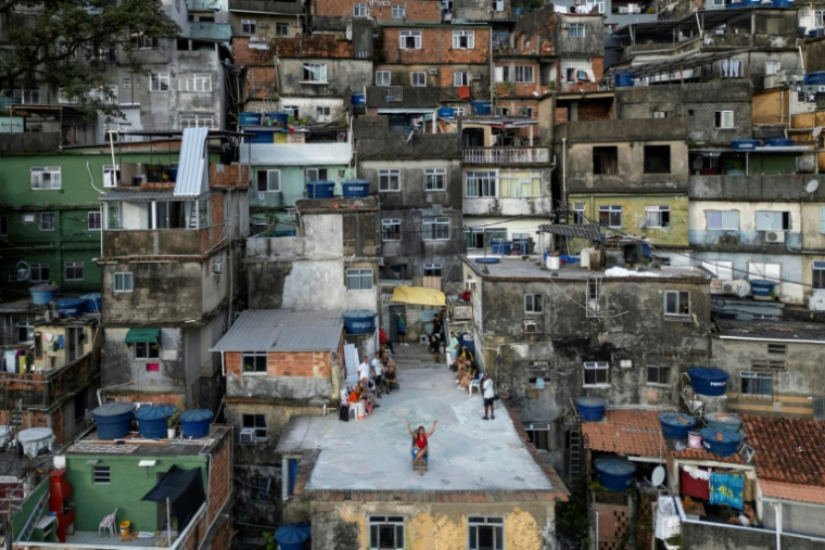 Vue aérienne d'une touriste se faisant filmer par un drone sur le toit d'une maison dans la favela de Rocinha, à Rio de Janeiro, au Brésil, le 5 mars 2026 ( AFP / Pablo PORCIUNCULA )