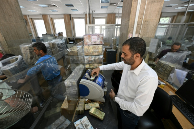 Des employés de la banque centrale de Damas comptent des piles de livres syriennes, le 21 mai 2025 ( AFP / LOUAI BESHARA )