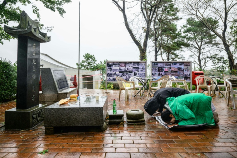 Sur cette photo prise le 7 octobre 2025, Ryh Jae-hong (2e à droite, vêtu de noir), fils d'un réfugié nord-coréen, se prosterne devant un autel sur l'île de Gyodong ( AFP / ANTHONY WALLACE )