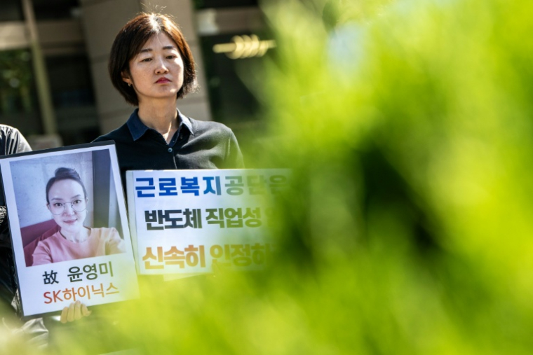 Militants et proches brandissent le portrait d'une ancienne employée de SK hynix, lors d'un rassemblement devant une antenne du Service sud-coréen d'indemnisation et de protection sociale des travailleurs, à Séoul, le 7 octobre 2026 ( AFP / Philip FONG )