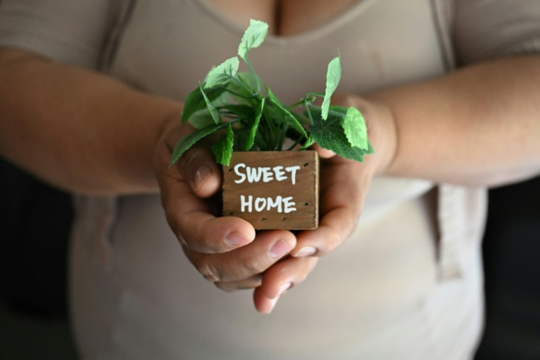 Martha, une sans-papiers mexicaine utilisant un pseudonyme, montre une décoration de son appartement avec le slogan "Doux Foyer", à Buena Park, près de Los Angeles, le 31 juillet 2025 ( AFP / Robyn Beck )