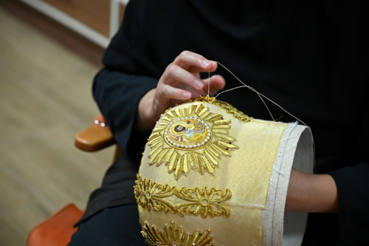 La religieuse chrétienne orthodoxe sœur Élisabeth brode au fil doré des motifs et détails sur une mitre, au monastère de Saint-Georges le Victorieux à Rajcica, le 18 juin 2025 en Macédoine du Nord ( AFP / Robert ATANASOVSKI )